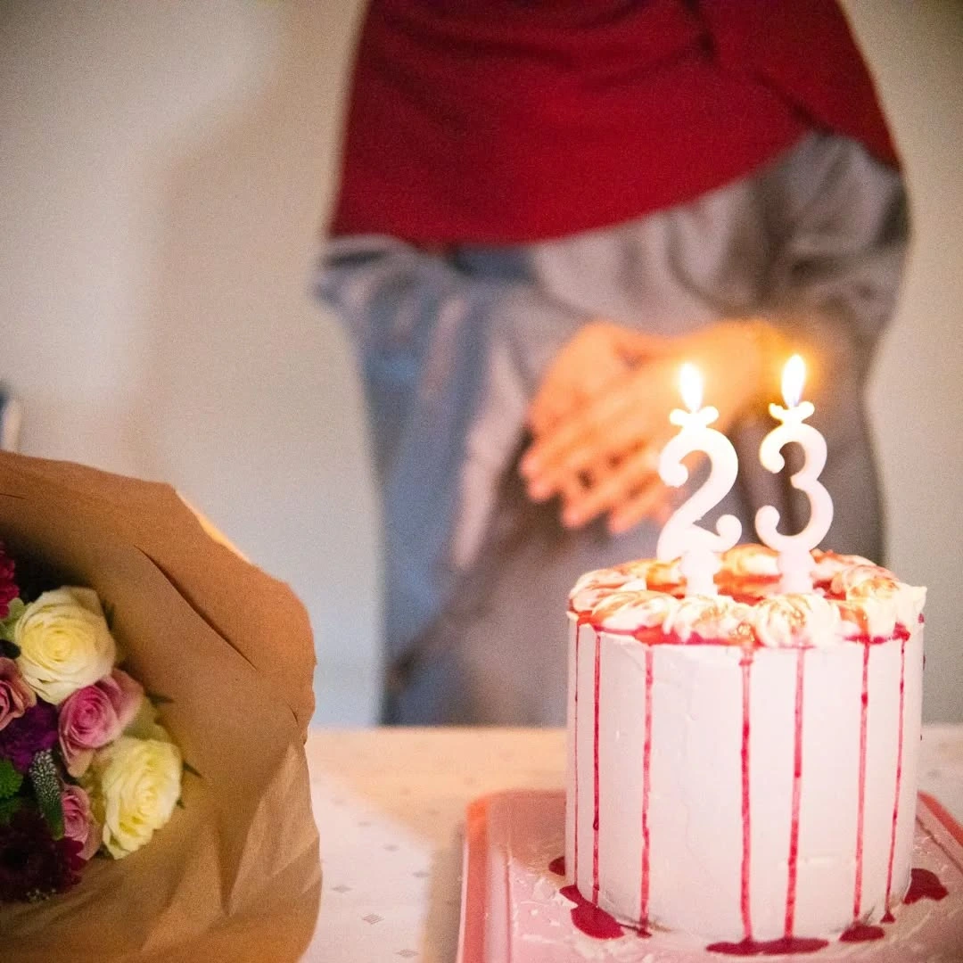 Gâteau d'anniversaire tenu à deux mains, bougies allumées